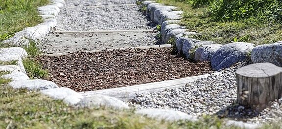 Bild zeigt Ausschnitt aus einem Barfußweg mit verschiedenen Materialien gestaltet